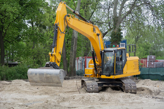 Crawler excavator with operator at work on a construction site during earthworks and site preparation, deeper yellow tones