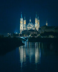 Obraz premium Illuminated Basilica del Pilar cathedral with reflection on Ebro river at night in Zaragoza, Spain