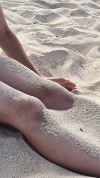 Child playing with fine sand, letting it slip through both hands in a time concept video about experience and passing time. Close up