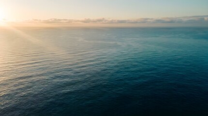 Obraz premium Calm blue ocean waves reflecting the golden warm sunlight during a peaceful early morning sunrise scene