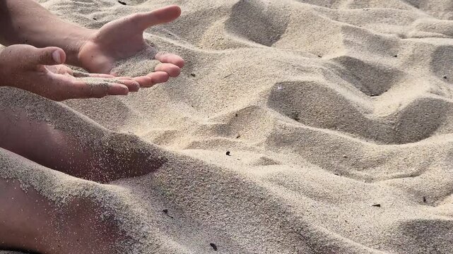 Child playing with fine sand, letting it slip through both hands in a time concept video about experience and passing time. Close up