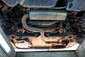 Fototapeta premium Undercarriage View of Car Exhaust System, Suspension and Chassis Components in Auto Repair Inspection Pit