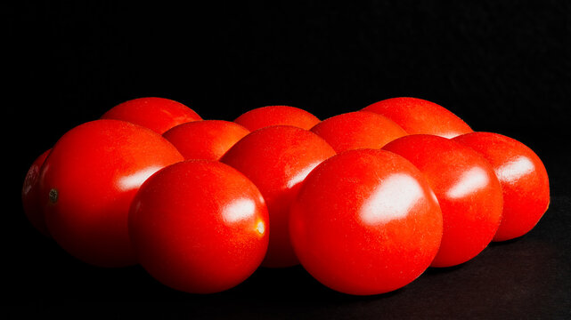 Bright red cherry tomatoes isolated against a black background