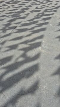 Sombra de bandeirolas balan&ccedil;ando ao vento, no ch&atilde;o de concreto.