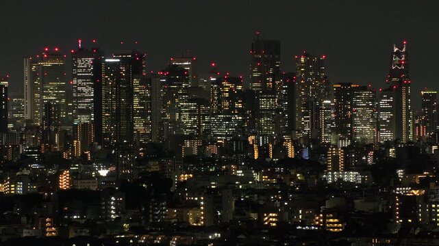 TOKYO, JAPAN - JUNE 2026 : Aerial time lapse shot of Shinjuku city at night. View of crowded office buildings in downtown area. Japanese urban city and business concept video.
