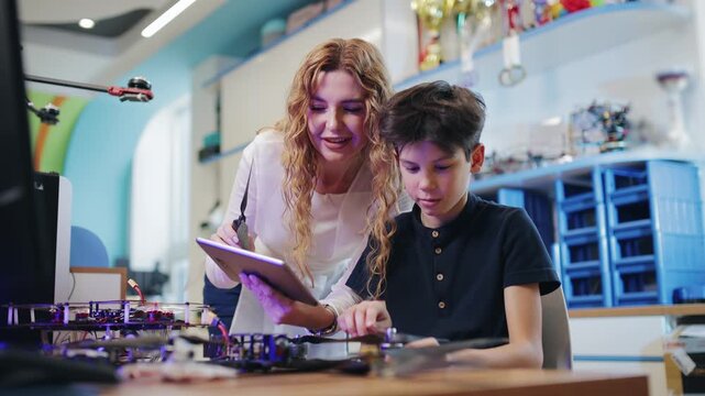 Female instructor guiding boy assembling Robot drone in workshop. Robotics intelligence education for child in classroom.