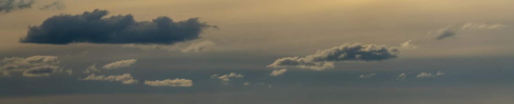 Panorama of evening clouds in shades of blue and pale yellow filling the frame. Only the clouds are included in the image
