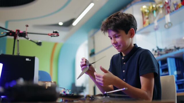 Boy holding robot drone at workbench in classroom lab. Robotics and intelligence technology education for young scientist child.
