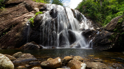Fototapeta premium Waterfall cascading over rocks in lush green forest