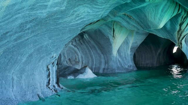 Boat view inside the Marble Caves, highlighting water-eroded swirling patterns on stone walls and vibrant turquoise glacial water in General Carrera Lake, Patagonia, Chile.