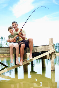 Family, dad and fishing with teenager, lake and bonding with son on holiday or connection in nature. Outdoor, water and man with rod to catch fish, learn and laughing with boy on vacation and hobby