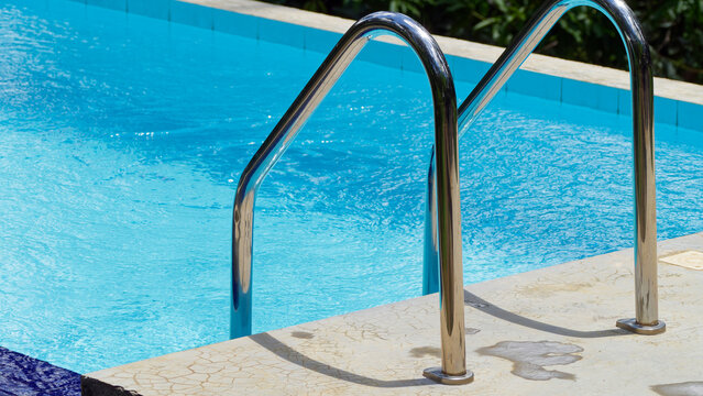 Swimming pool ladder with glistening blue water