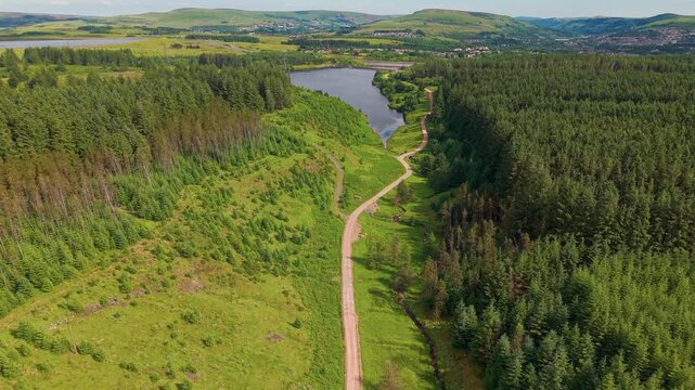 Aerial view of Carno Reservoir surrounded by dense green forest in South Wales