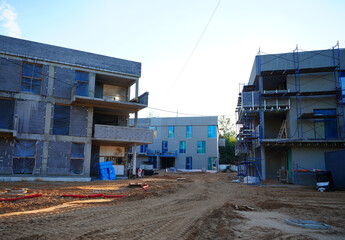 Fototapeta premium Apartment building under construction. Development cityscape with urban villa in low-density residential area. Business-class monolithic house with flats under construction. 