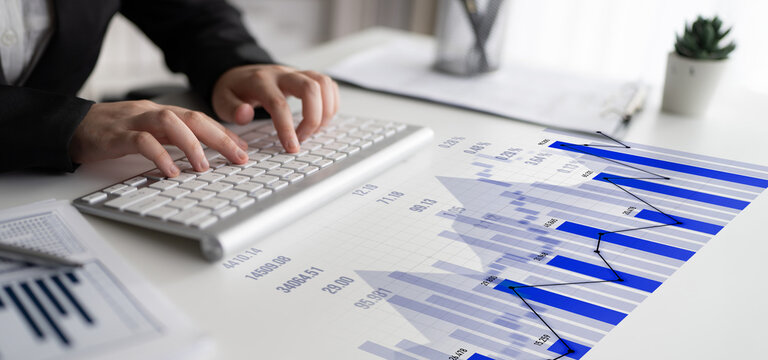 A focused individual types on a keyboard in a modern workspace filled with financial charts and graphs, emphasizing the importance of data analysis in business success. Scalp