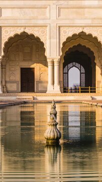 Vertical video: Jetting stone finial spraying water in courtyard, rippling pool to animate mirrors