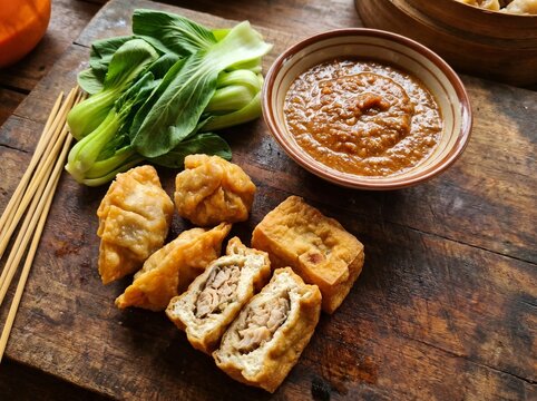 Authentic Indonesian Fried Dim Sum Batagor With Peanut Sauce and Fresh Bok Choy Served on Rustic Wooden Board