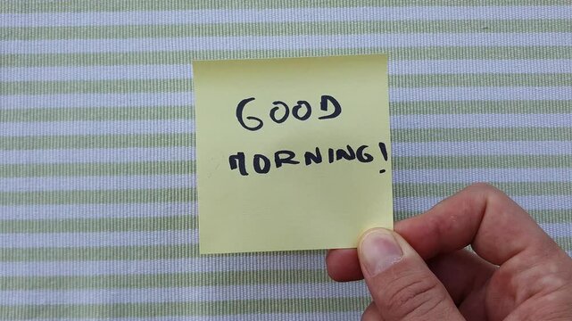 Hand removing a Good Morning sticky note to reveal a cup of hot espresso coffee.