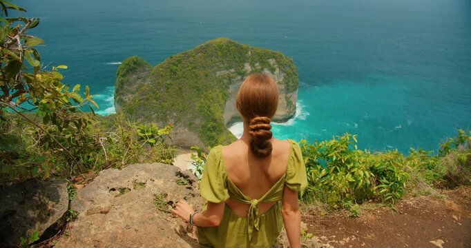 Back view of woman looking at T Rex bay Kelingking beach on Nusa Penida Island in Indonesia