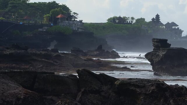 Silent Coastal Temple. Misty Shoreline With Ancient Shrine. Eroded Rocks Leading To Tranquil Sacred Site. Serene Landscape Featuring Weathered Stones And Distant Spiritual Monument, Tanah Lot temple