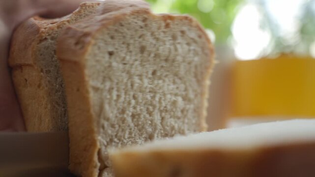 Hand cuts soft bread slice with knife. Concept of bread preparation and simple cooking