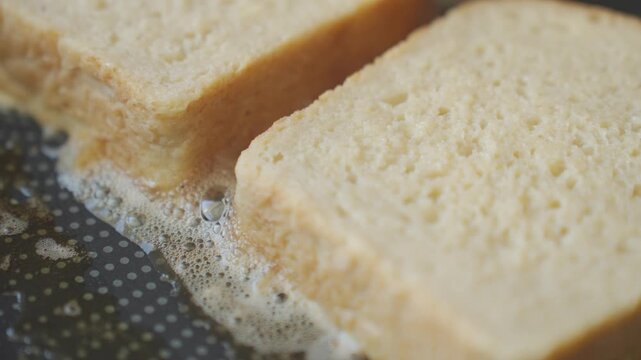 Bread slices cook on frying pan. Concept of French toast, breakfast preparation and simple homemade food