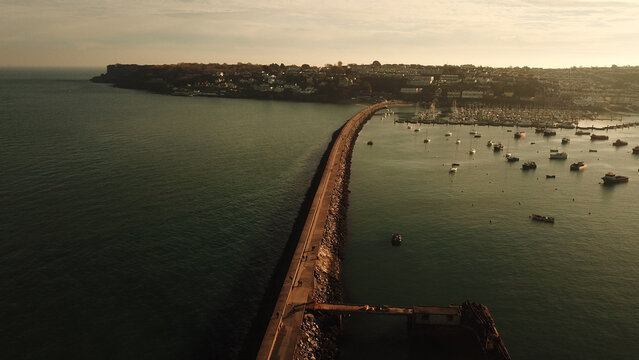 Aerial view of the breakwater and harbor in Brixham with boats moored in the marina under a soft sunset light, Brixham, England, United Kingdom.