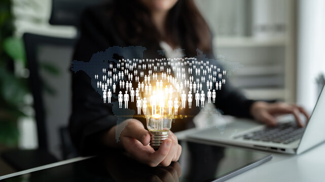 Business professional holding light bulb with digital people network overlay representing innovative ideas and global connectivity in modern workspace Quark.