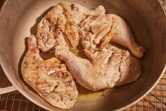 Whole chicken legs and thighs browning in a pot.