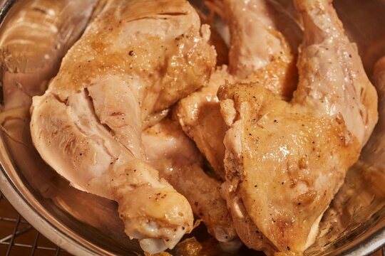 Browned whole chicken legs in a steel bowl.