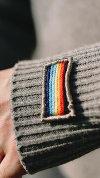 Vertical video: Approaching finger pressing pinching tugging patch on gray cuff indoors fixing fray