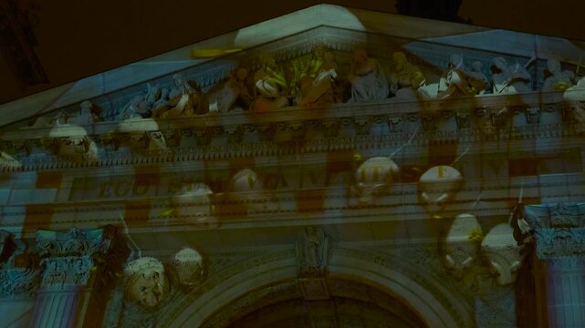 Colorful video mapping show on an ancient church facade. Dynamic and vibrant animation projected onto a historic religious building, creating an immersive light show with moving shapes and colors