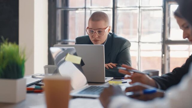 Female office worker thinking about dismissal from work, portrait in office. Stylish young adult woman sitting in workplace, looking at laptop display and feeling sad, dissatisfaction and depression