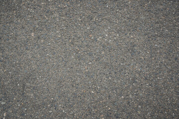 Fototapeta premium Grainy asphalt road surface with small stones and natural texture fills the frame, creating a detailed urban background for construction, transportation and infrastructure concepts