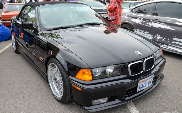Mint condition black BMW 3 Series Convertible E36 showcasing the peak of 1990s German automotive design at a car culture festival