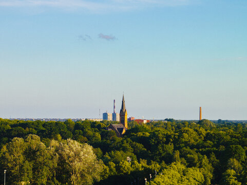 Aerial view of Riga Luther Church surrounded by dense green trees and urban skyline in Riga, Latvia.