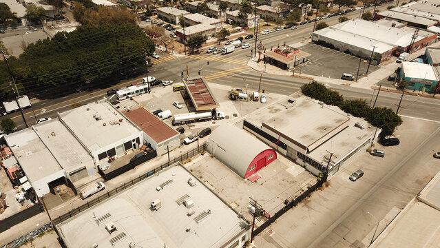 Aerial view of industrial buildings, a gas station, and a distinctive red Quonset hut situated at a street intersection in East Los Angeles, California, United States.