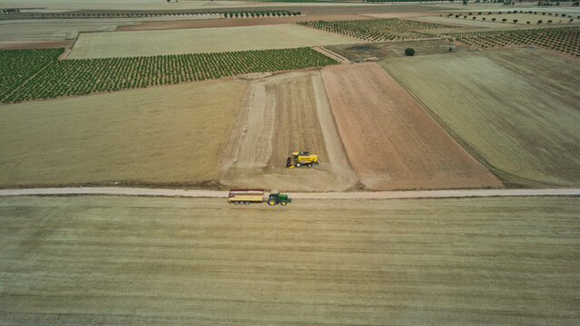 Aerial view of combine harvester harvesting ripe wheat field in summer countryside. Castilla-La Mancha, Spain - June 7, 2026.