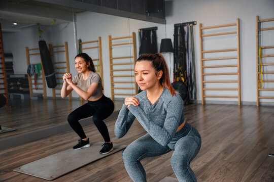 Two women exercise together in a gym, focusing on their workout routine during a training session