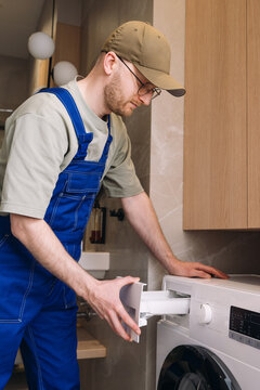 Male repairman inspecting automatic washing machine in modern house