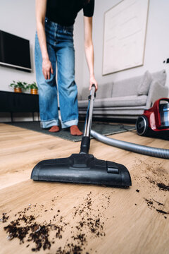 Woman cleans the floor in an apartment using a vacuum cleaner