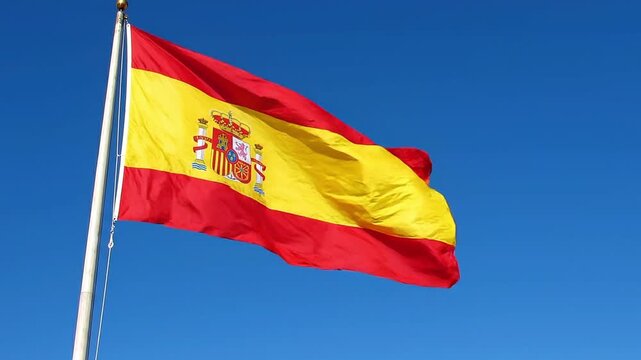 Spanish flag waving against a clear blue sky