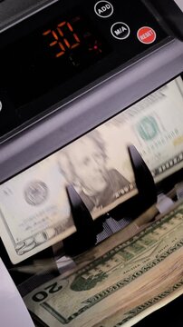 Money counting machine. Currency counting machine counting US money. Slow Motion, vertical video.