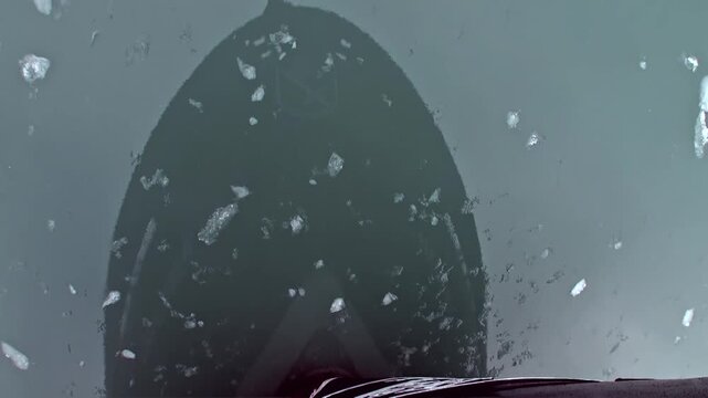 A powerful ship's bow carves a path through shimmering ice shards in the frigid Arctic waters off Svalbard, Norway. This unfolds during the unique summertime, revealing polar navigation.