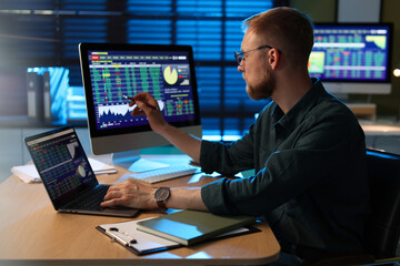 Fototapeta premium Financial trading specialist working with laptop at wooden desk in office