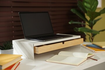 Naklejka premium Workplace with laptop on riser stand and stationery indoors, closeup