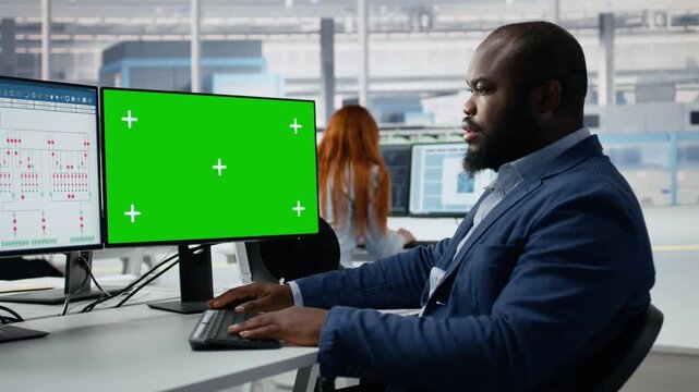 Green screen mockup PC used by man in semiconductor factory office analyzing PCB architecture, African American engineer monitoring microchip parts fabrication on chroma key computer.
