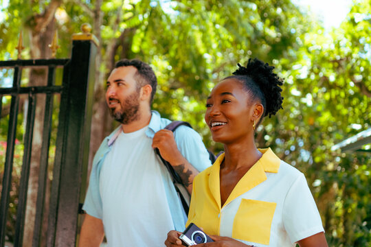 Diverse couple exploring new city holding compact camera