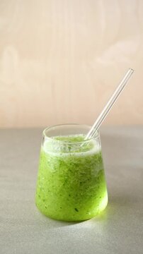 put a straw in a glass with a green smoothie