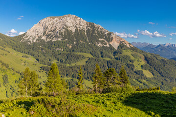 Fototapeta premium Rocky mountain summit in the Austrian Alps near Salzburg, Austria. Jagged cliffs, steep slopes, and rugged alpine terrain dominate the landscape, while surrounding mountain ranges stretch toward the h